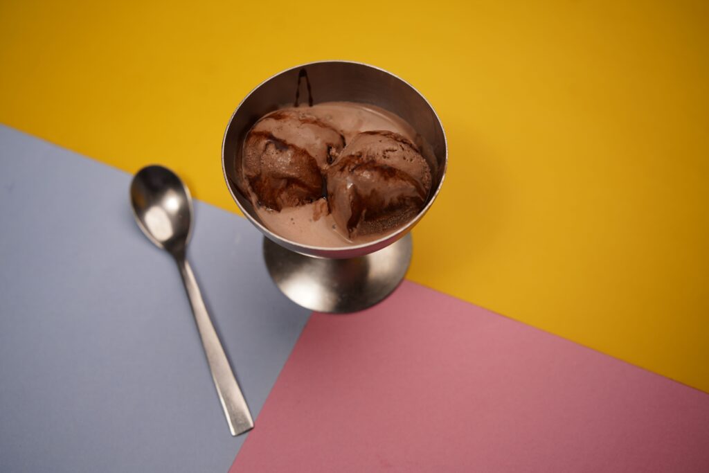 Delicious chocolate ice cream served in a metal cup with a colorful geometric background, perfect for food photography.
