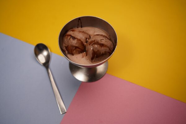 Delicious chocolate ice cream served in a metal cup with a colorful geometric background, perfect for food photography.
