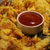 Golden crispy chips served with a bowl of tomato ketchup, perfect snack delight.