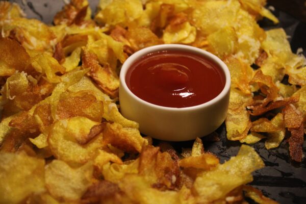 Golden crispy chips served with a bowl of tomato ketchup, perfect snack delight.